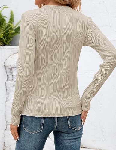 Woman wearing beige long-sleeve top and jeans, back view