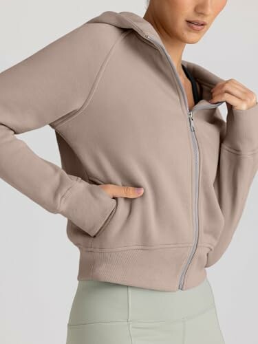 Person wearing a beige zip-up hoodie and light green leggings.