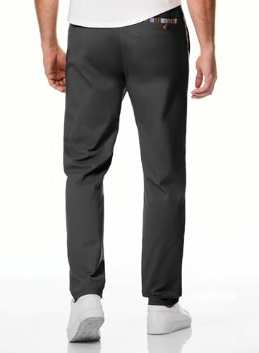 Back view of person wearing black trousers and white shoes.