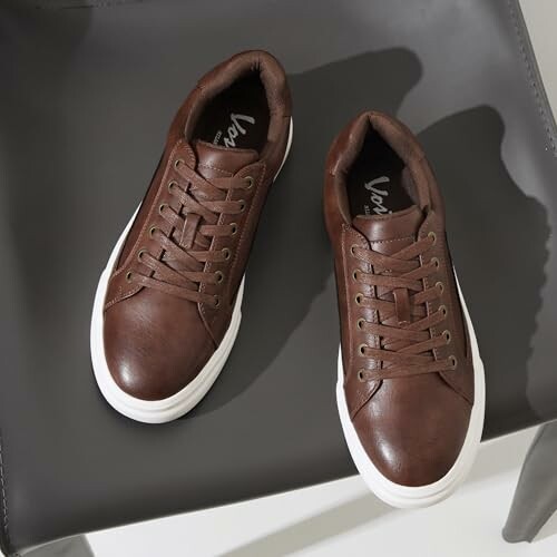 Brown leather sneakers with white soles on a chair