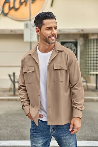 Man in beige jacket and jeans standing outdoors