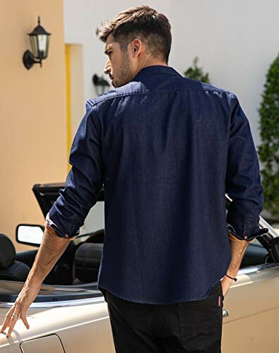 Man in denim shirt standing by a convertible car