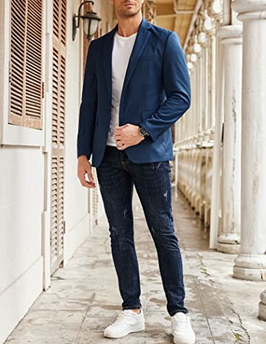 Man in blue blazer and jeans standing in a corridor