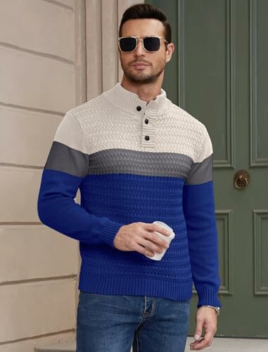 Man in sunglasses wearing a blue and gray sweater holding a cup