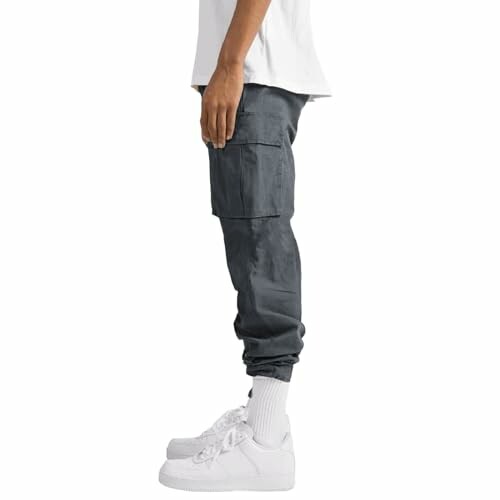 Side view of a person wearing dark cargo pants and white sneakers.