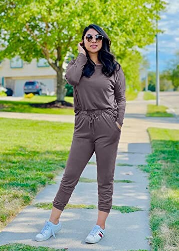 Woman in brown sweatsuit standing on a sidewalk outdoors