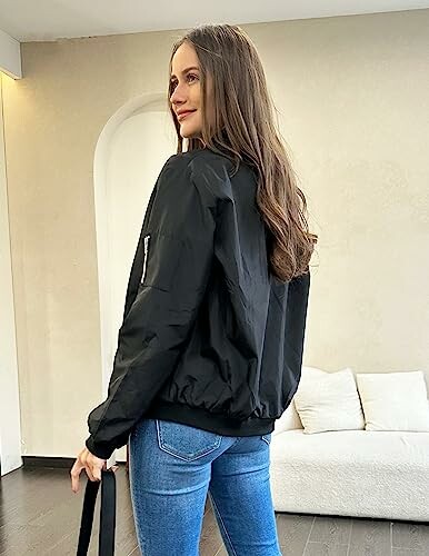 Woman wearing a black jacket and jeans in a room