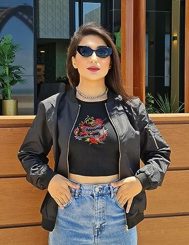 Woman in black jacket and sunglasses standing outdoors