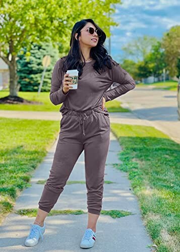 Woman in brown jumpsuit walking with a coffee cup