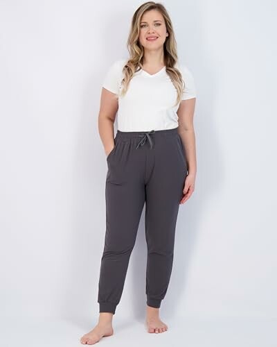 Woman wearing a white t-shirt and gray joggers.