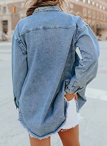 Woman wearing a blue denim jacket and white shorts on a city street.