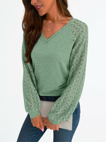 Woman wearing a green blouse with lace sleeves holding a clutch.
