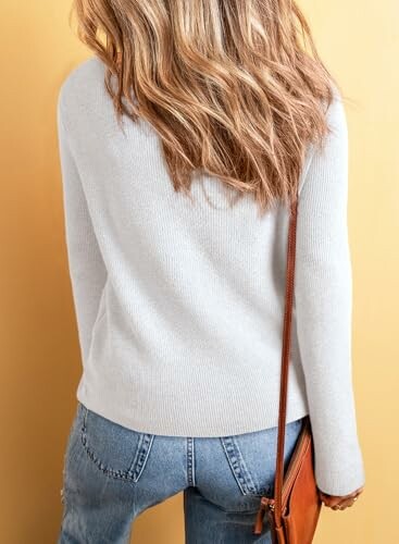 Woman in a light sweater and jeans with a brown bag