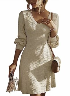 Woman in beige textured dress holding a small bouquet and bag.