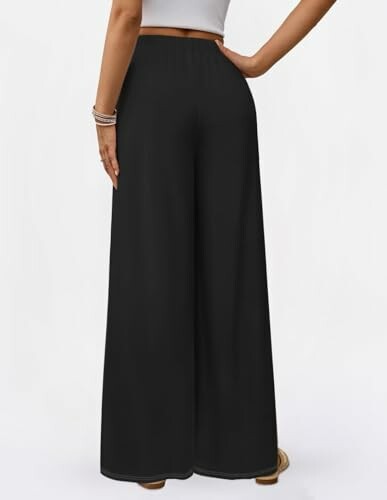 Woman wearing black wide-leg pants and a white top.